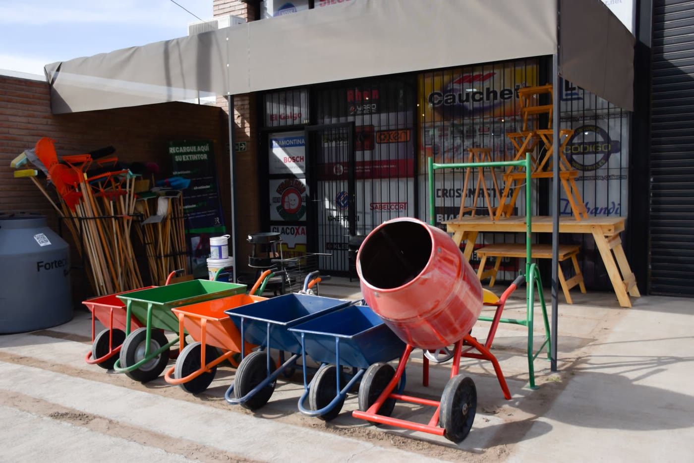 Carretillas de colores y una hormigonera en la vereda del corralón