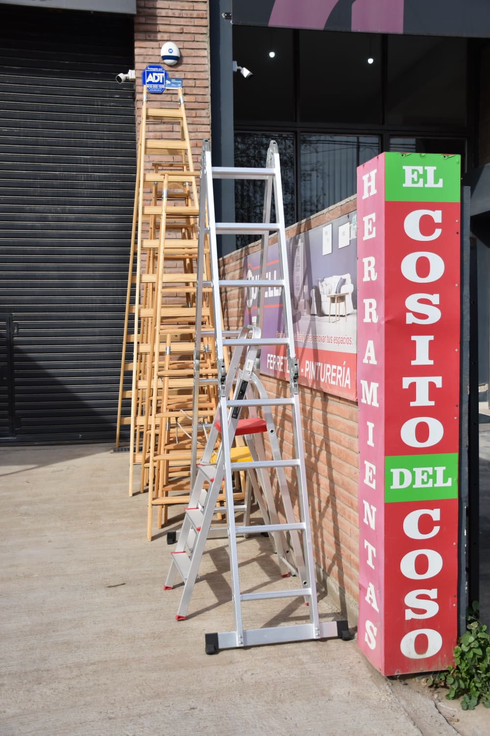 Escaleras de aluminio y de madera en la entrada del corralón