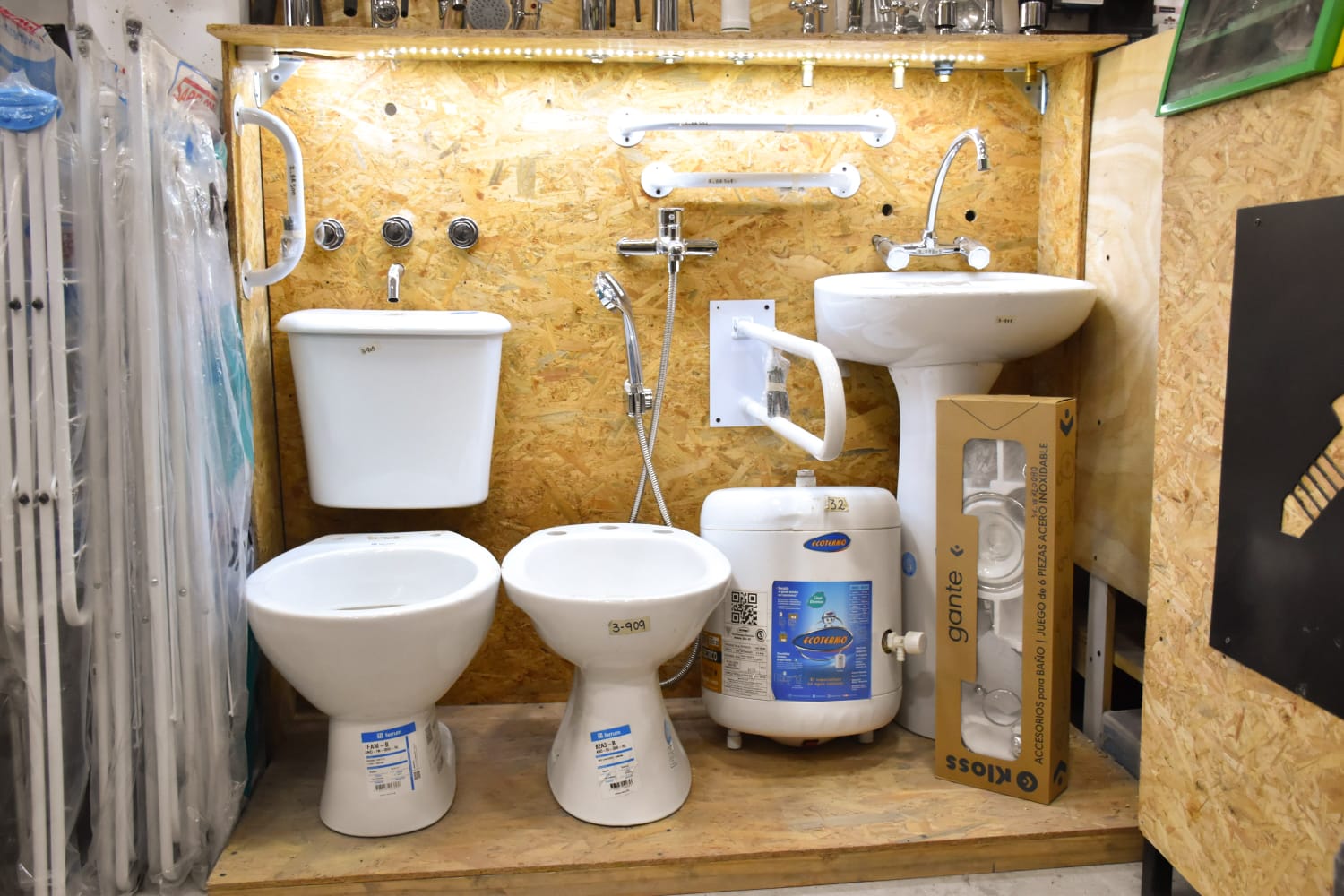Sector de sanitarios de El Cosito del Coso: inodoro, bidet, lavatorio, termotanque y la pared de griferías